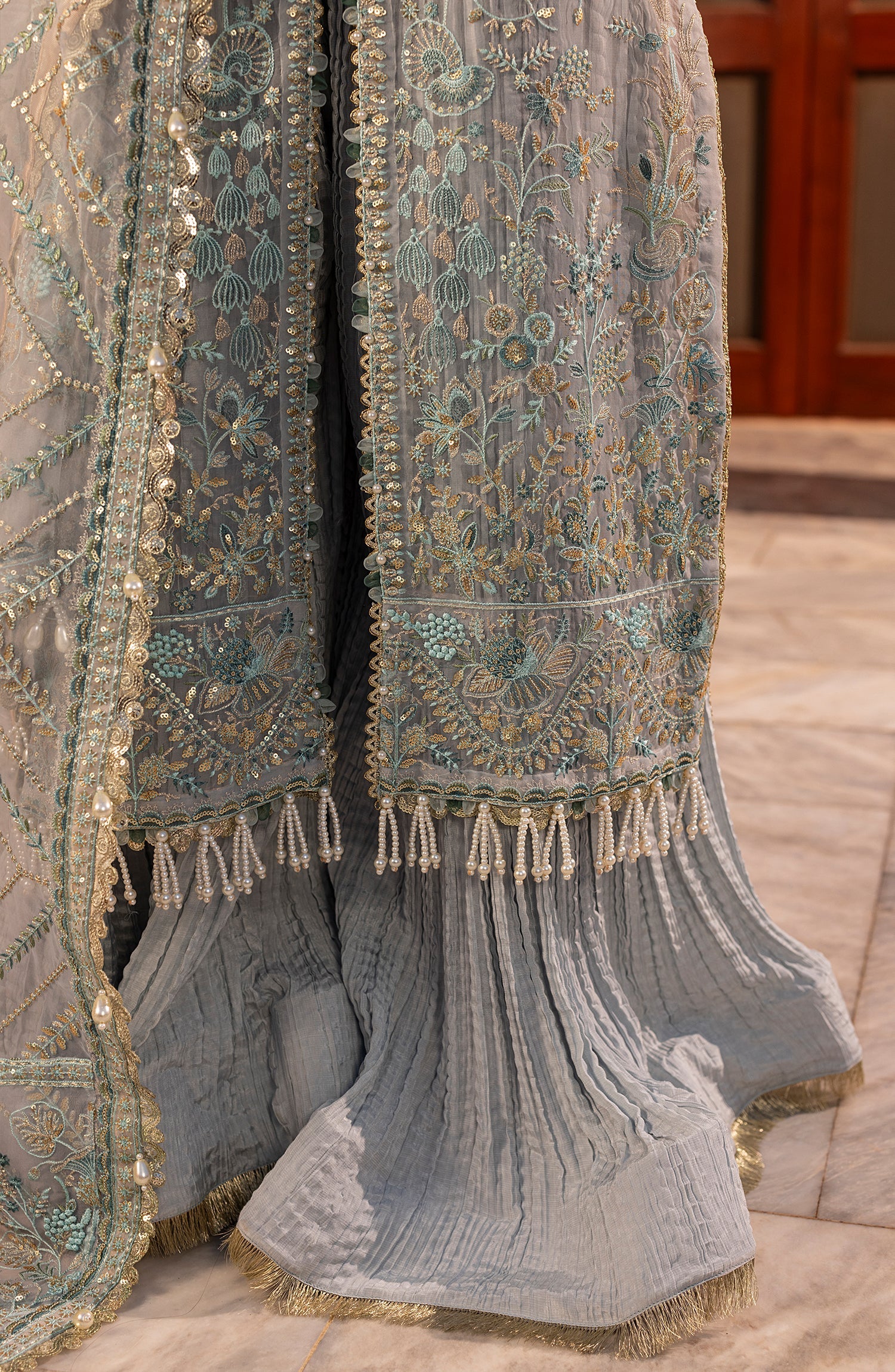 Decorative fabric with intricate patterns and tassels on a wooden floor.